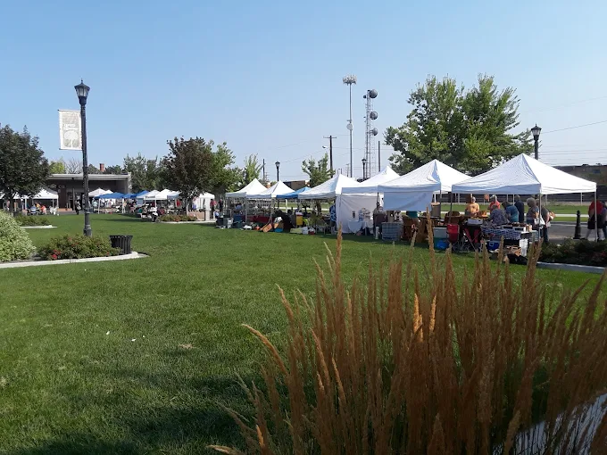 Nampa Farmers Market – Local Vendors and Fresh Finds White vendor tents set up on a green lawn at the Nampa Farmers Market in Idaho on a sunny day