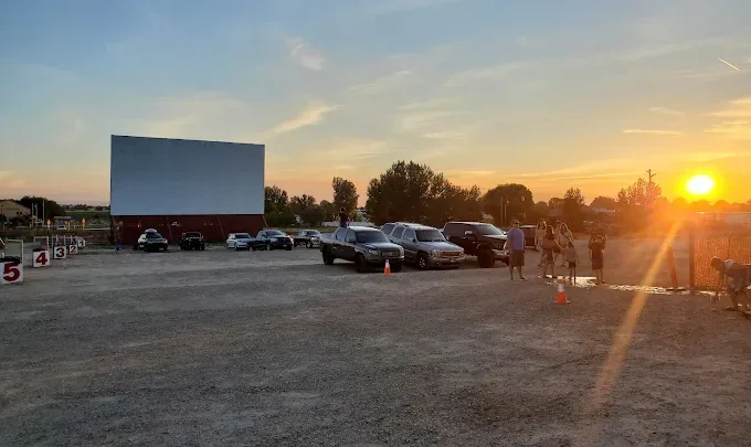 Cars parked in front of a large screen at Terrace Drive-In Theatre in Nampa, Idaho at sunset