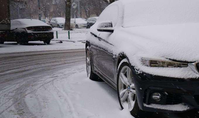 Car covered in snow parked on a winter road in Nampa ID, showing the need for seasonal auto repair and maintenance.
